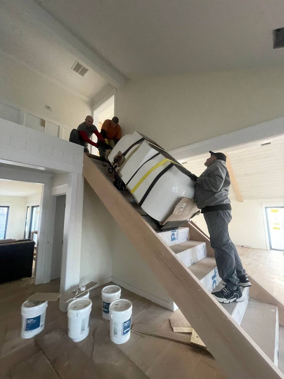 Three-man stair carry. Finished construction. Zero damage.